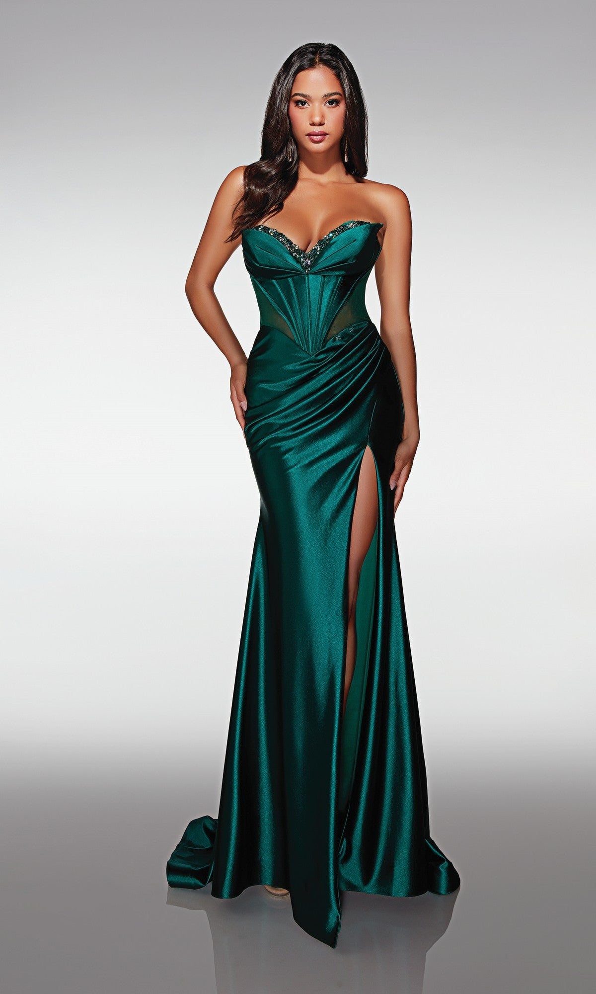 A woman in the Long Formal Dress: Alyce 62156—an emerald green strapless gown with a beaded sweetheart neckline, decorative accents, and a high thigh slit—stands against a plain background.